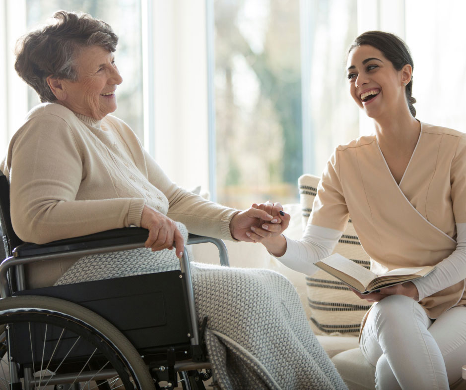 Image of older woman in wheelchair holding the hand of a younger woman