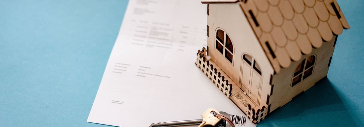 granny annexe insurance blog title image of a wooden house, keys and paperwork
